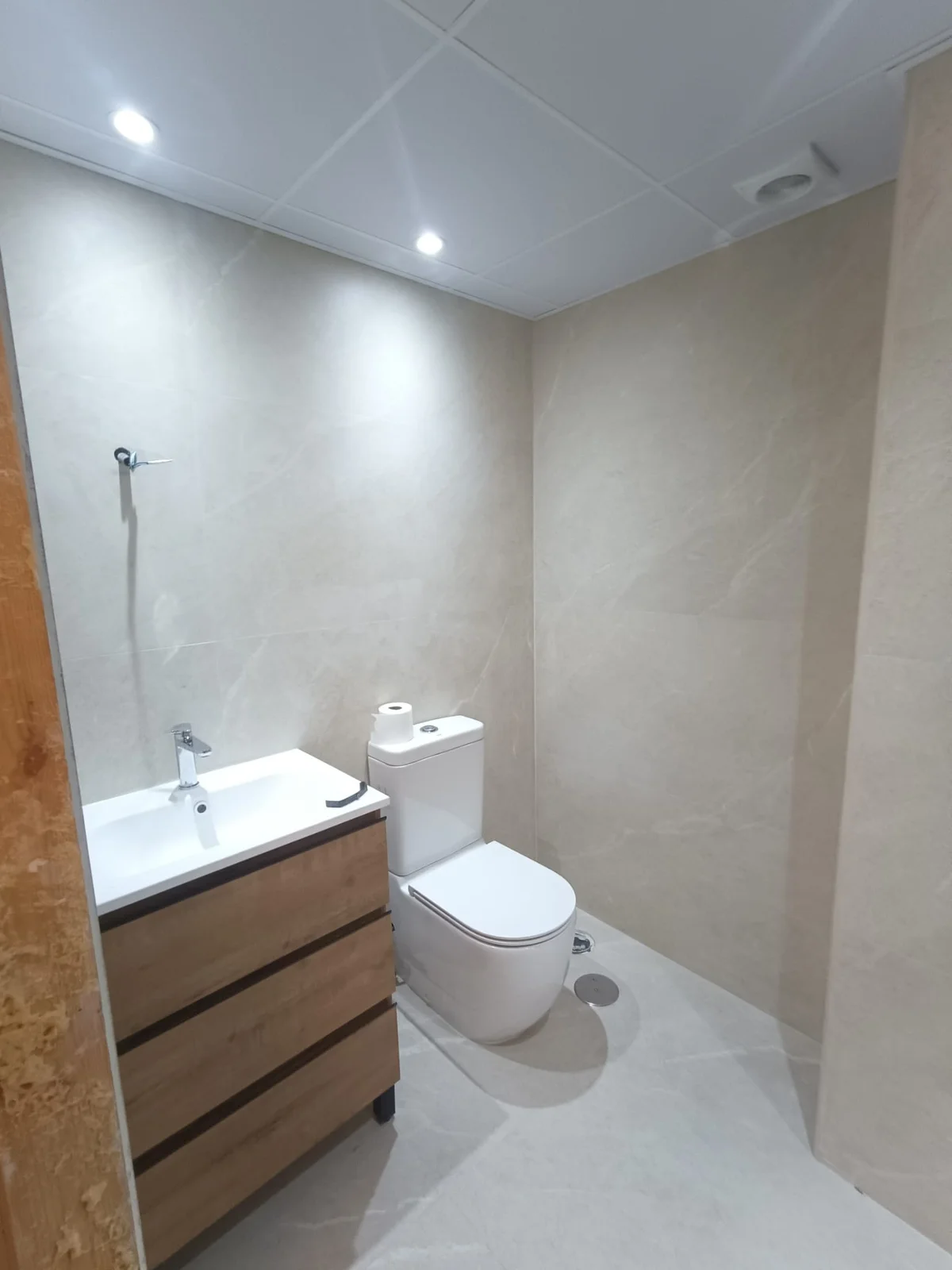 Baño terminado con mueble de madera, lavabo e inodoro suspendido