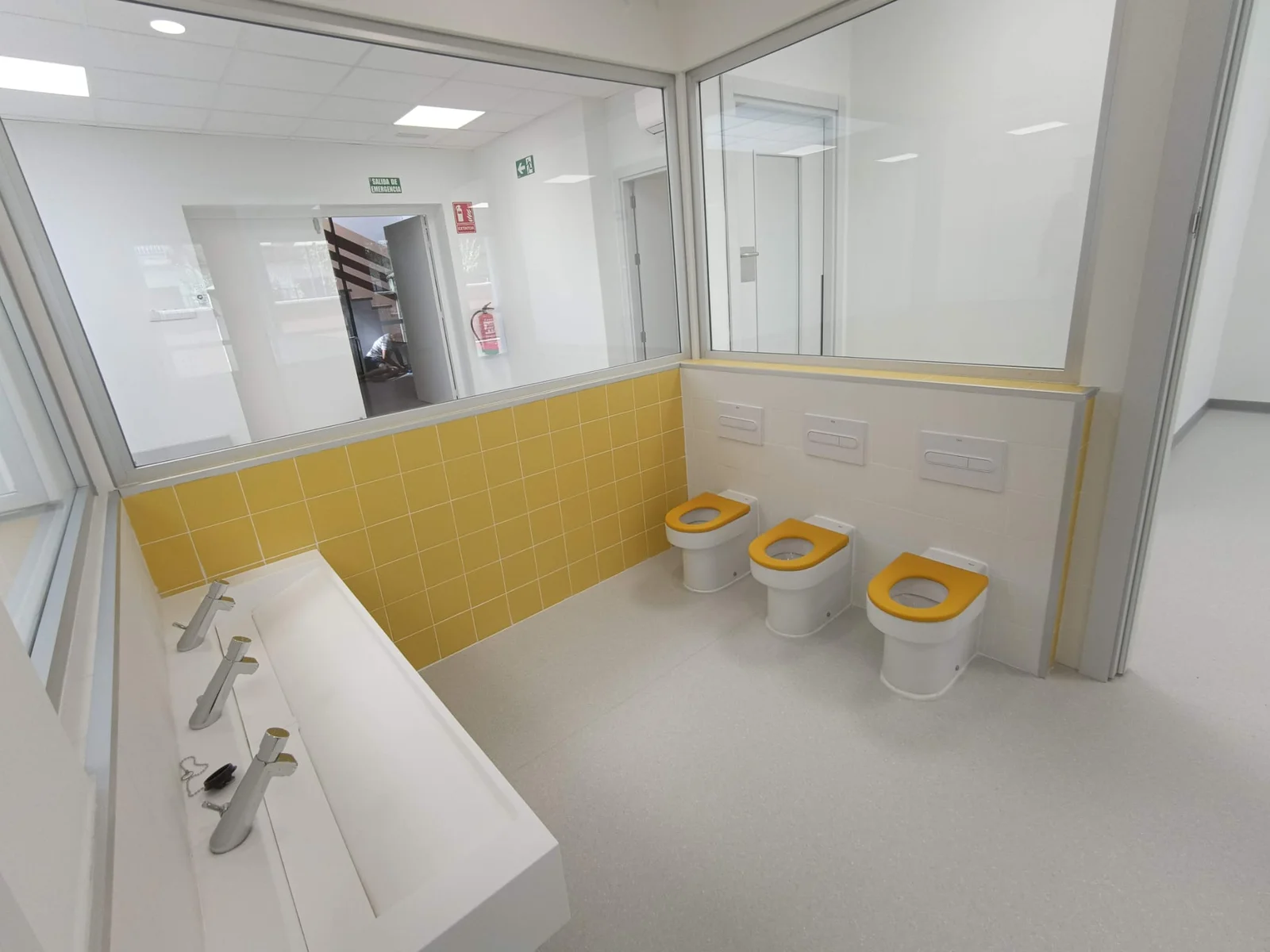 Aseo infantil con inodoros bajos y lavabo corrido amarillo