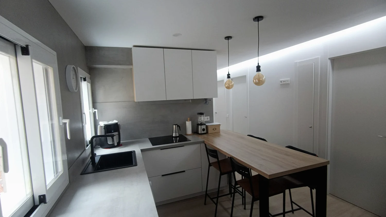Cocina terminada con office, mesa y lámparas colgantes